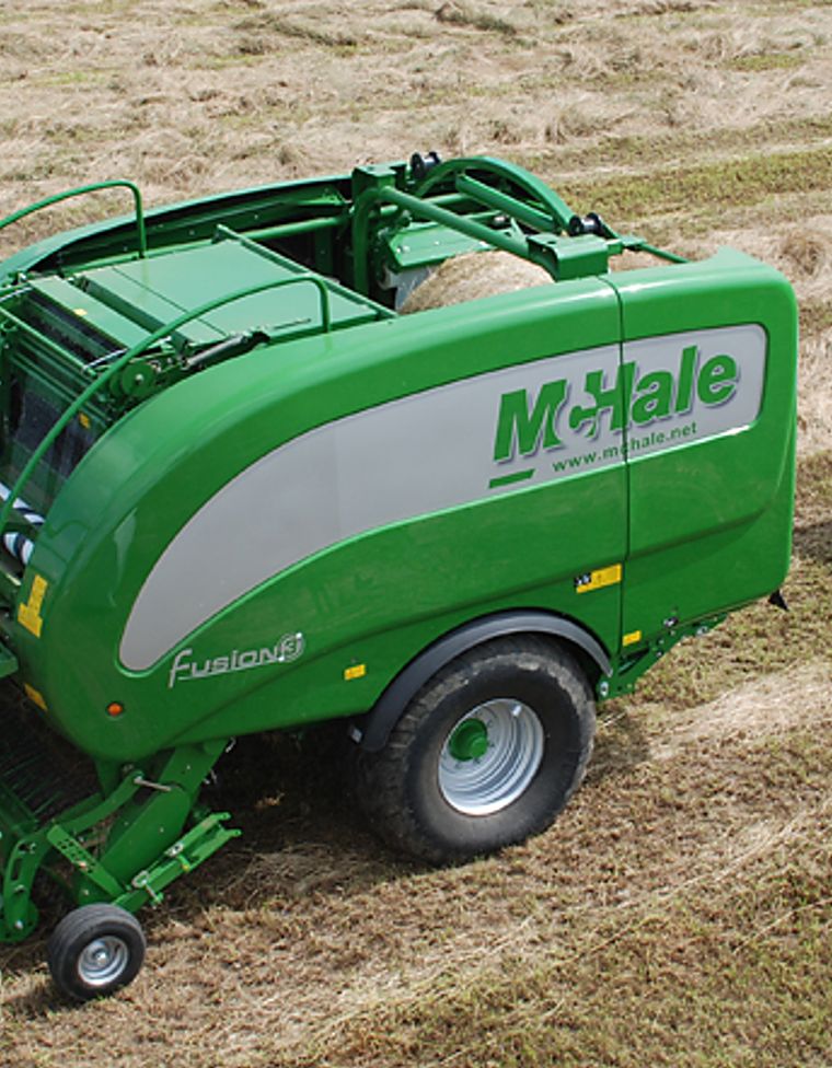 Presse-enrubanneuse McHale Fusion 3 dans une prairie, botte enrubannée à côté